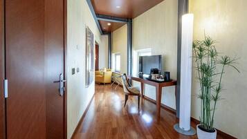 A hallway with wooden flooring, a sofa, a dining table, and a potted plant.