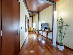 A hallway with wooden flooring, a sofa, a dining table, and a potted plant. - B&B HOTEL Imperia Rossini al Teatro (Imperia)