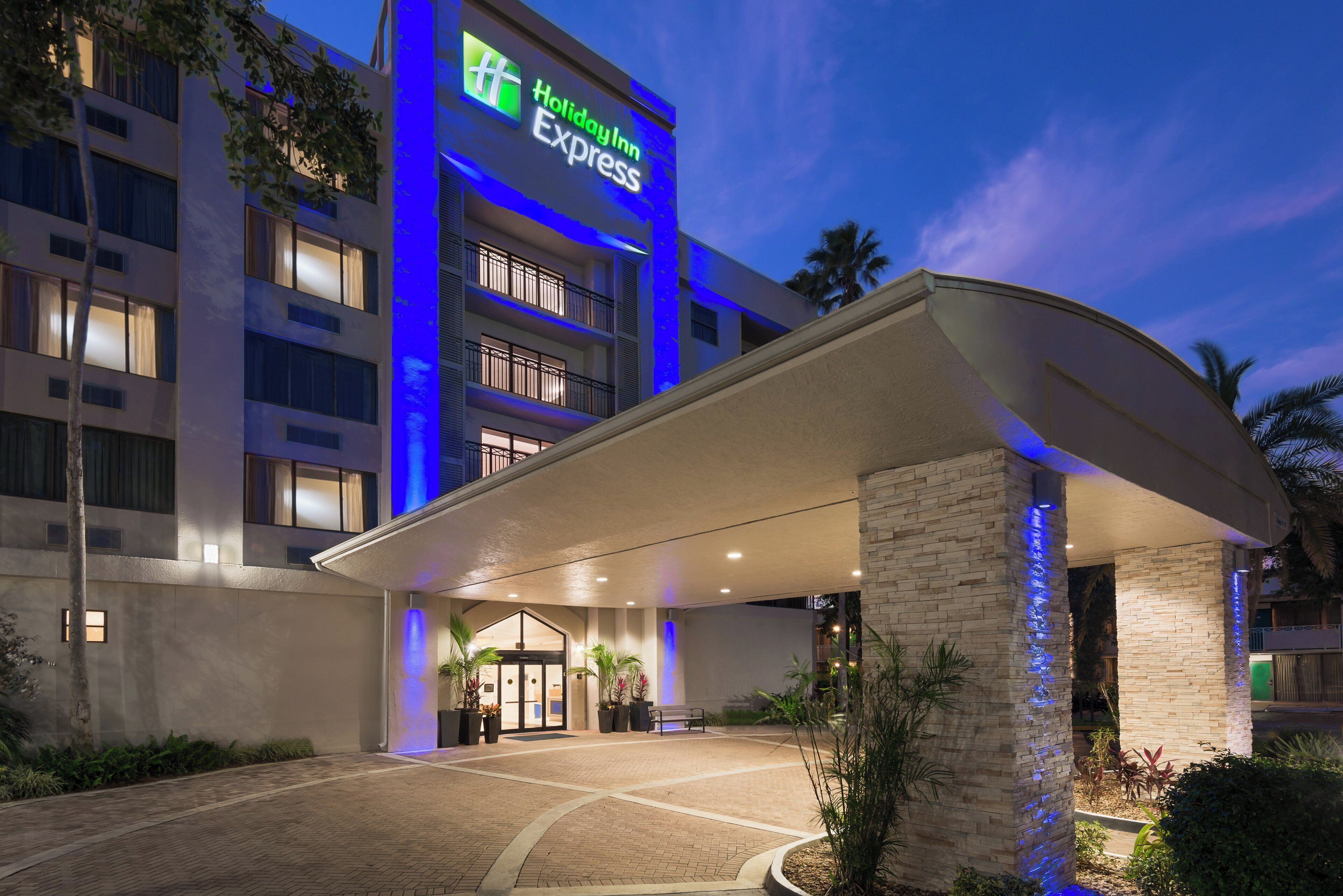A Holiday Inn Express hotel entrance with a covered walkway, potted plants, and a brick facade.