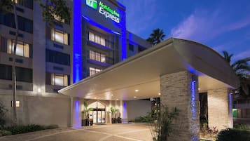 A Holiday Inn Express hotel entrance with a covered walkway, potted plants, and a brick facade.