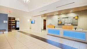 A hotel reception area with a reception desk, a vending machine, and a digital screen.