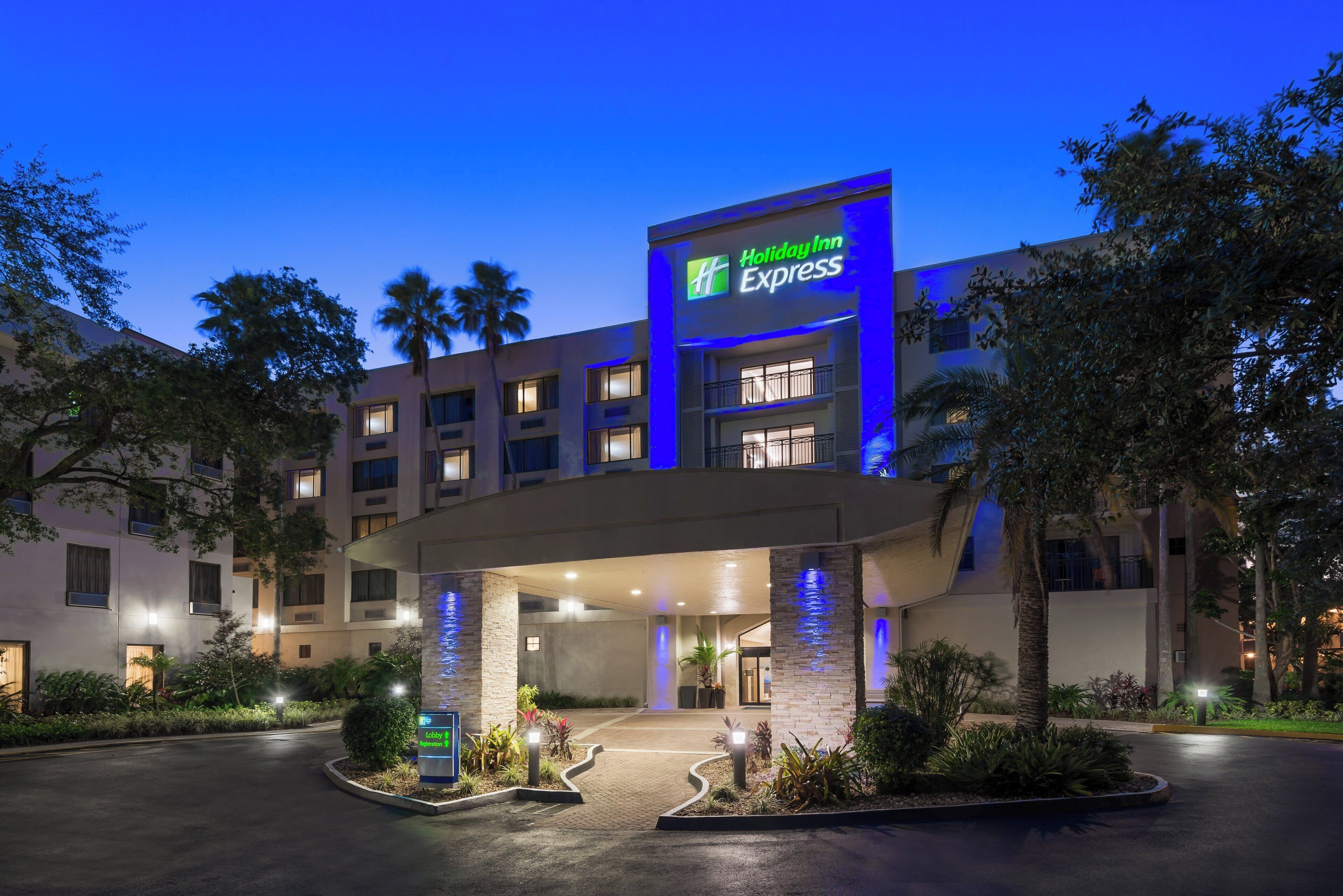 A Holiday Inn Express hotel with a modern design, featuring a prominent sign, multiple floors, and a landscaped entrance area.