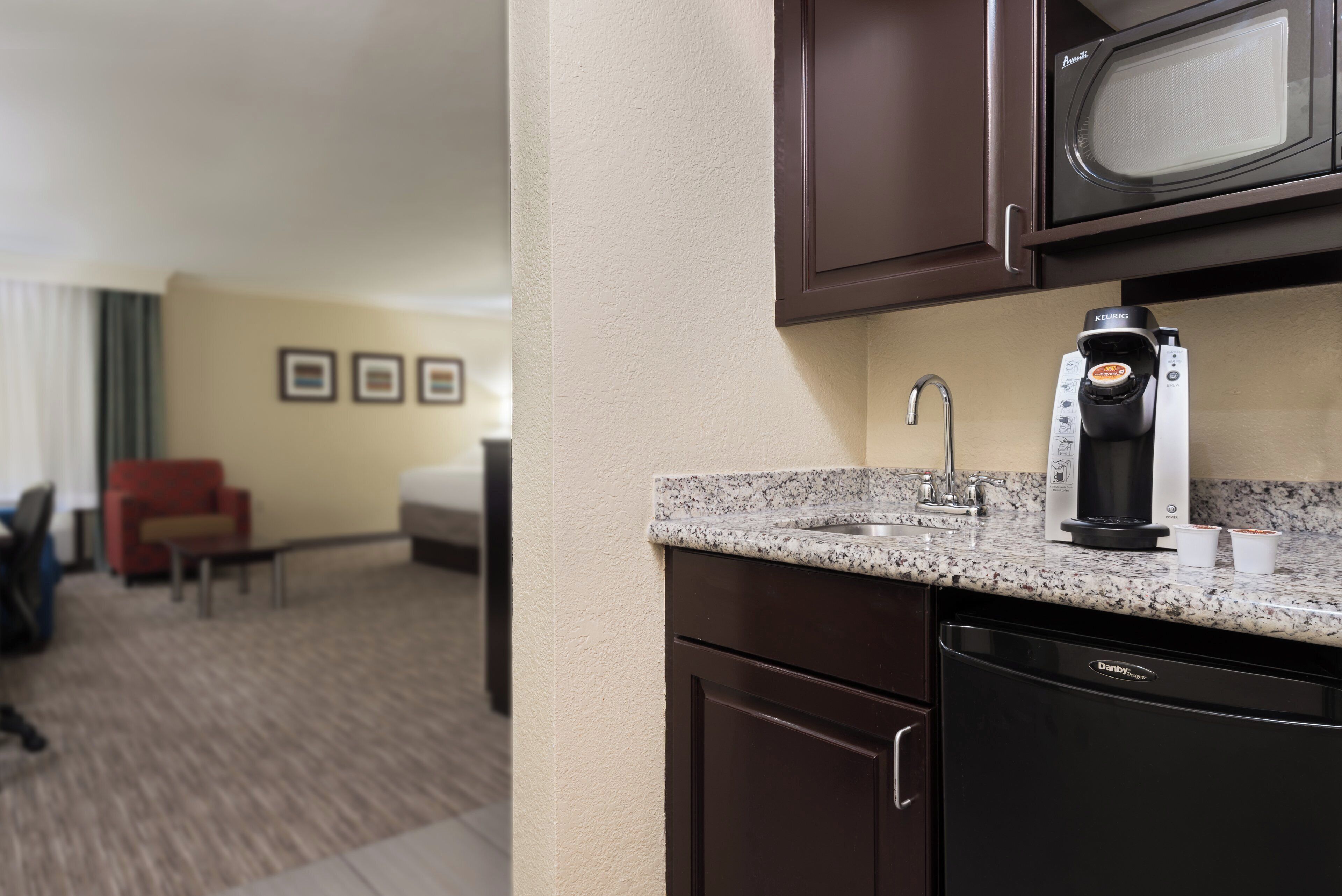 Una kitchenette con microondas, cafetera y lavabo.