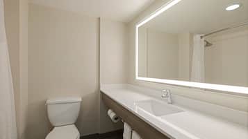 Un baño moderno con inodoro blanco, lavamanos y un espejo grande.