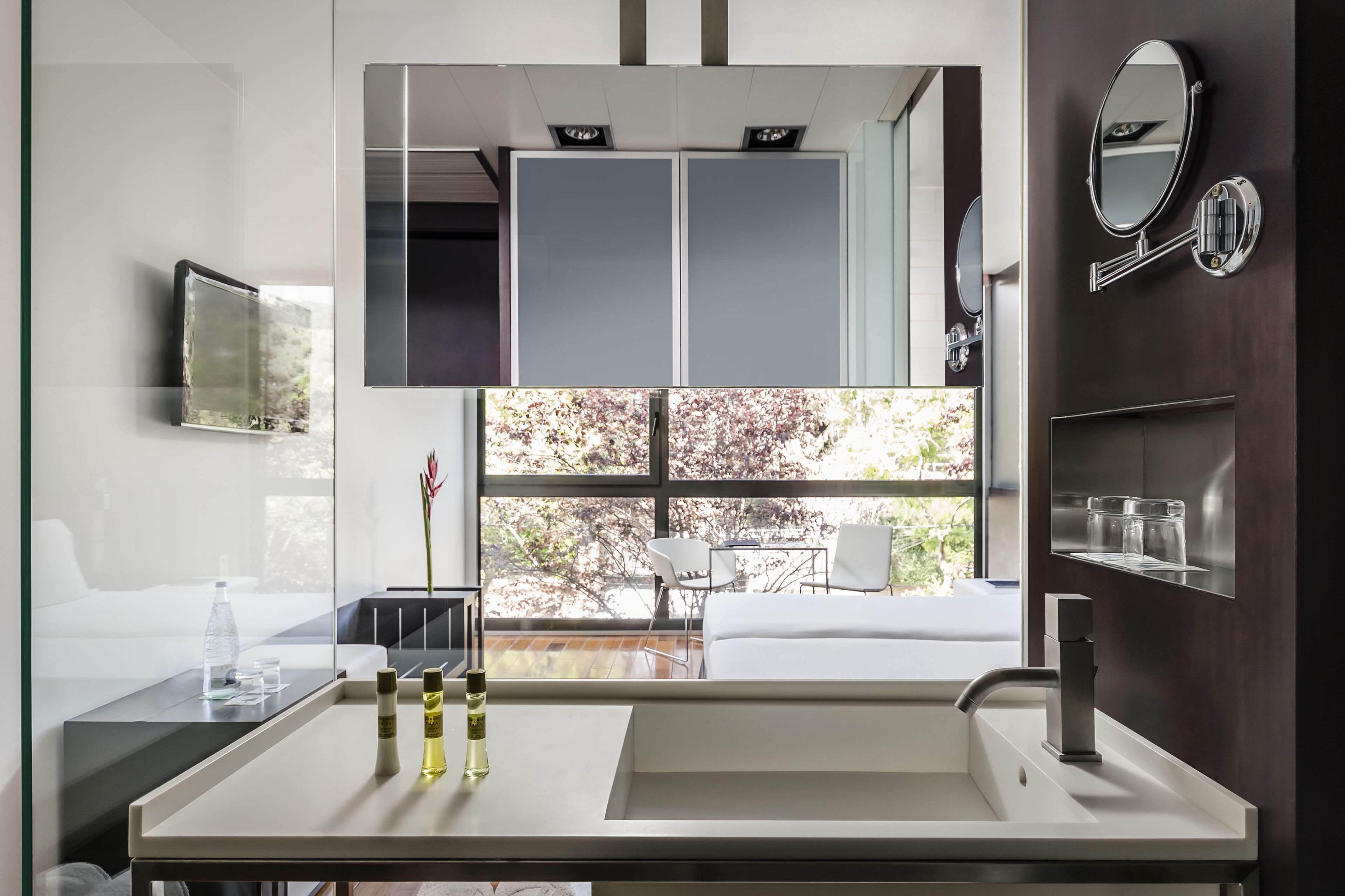 Un baño moderno con un espejo grande, un lavamanos y una ventana que ofrece vistas al exterior.
