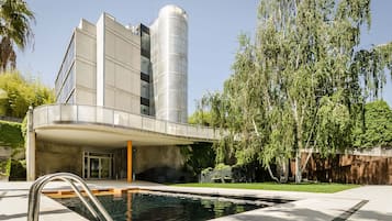 A modern building with a swimming pool, a covered walkway, and a cylindrical structure.