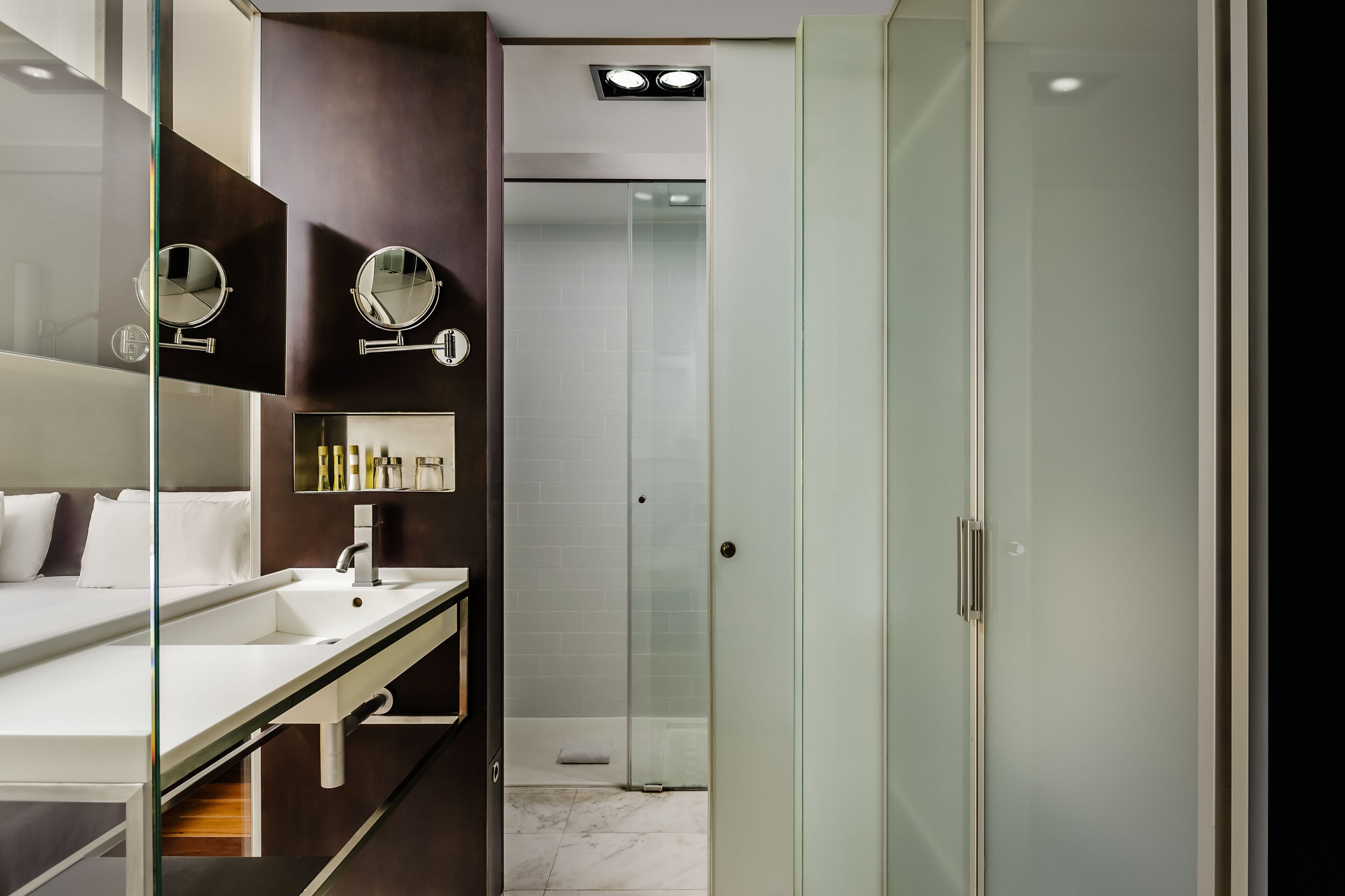 A modern bathroom with a glass shower enclosure, a vanity with a mirror, and a white sink.