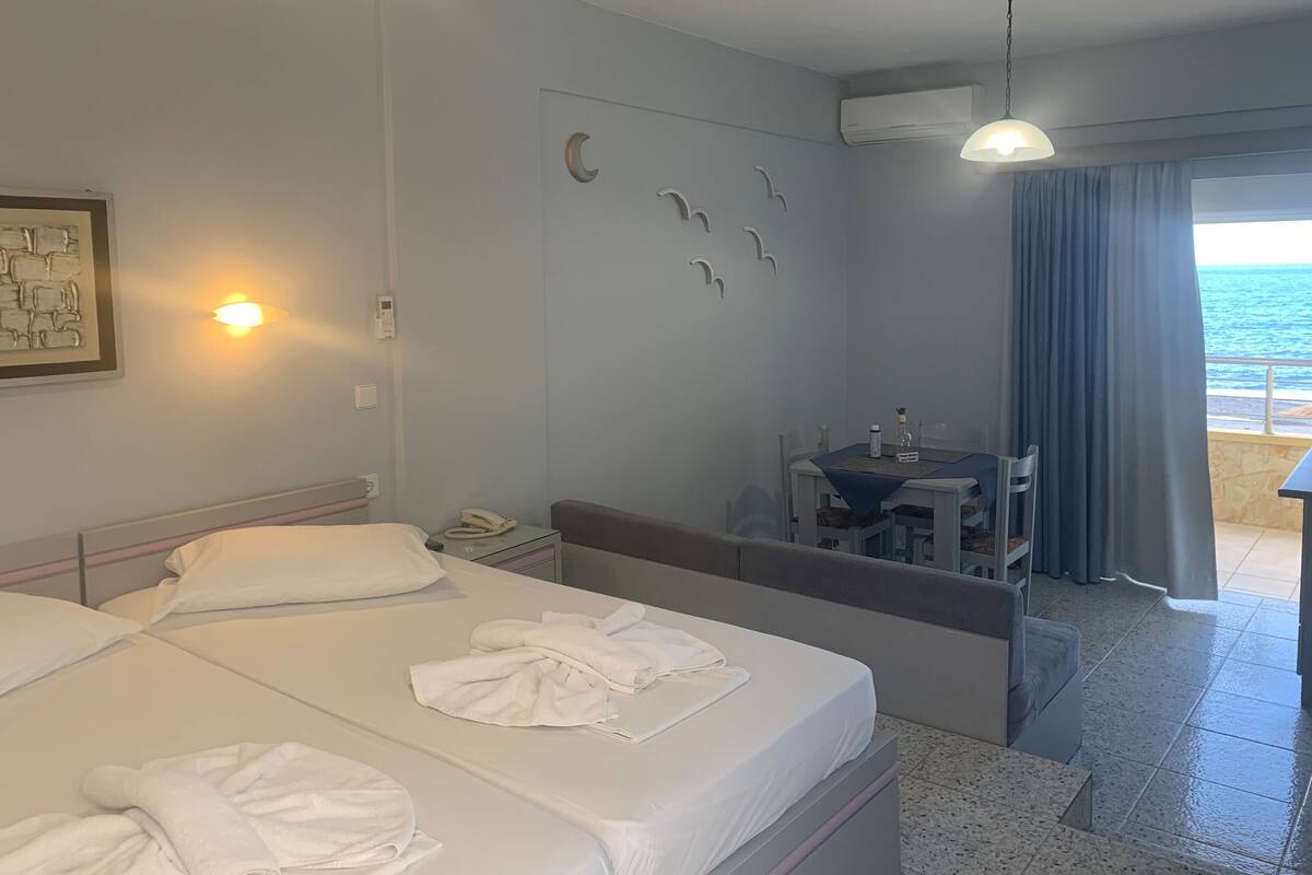Hotellihuone, jossa on kaksi sänkyä, työpöytä ja näköala merelle.