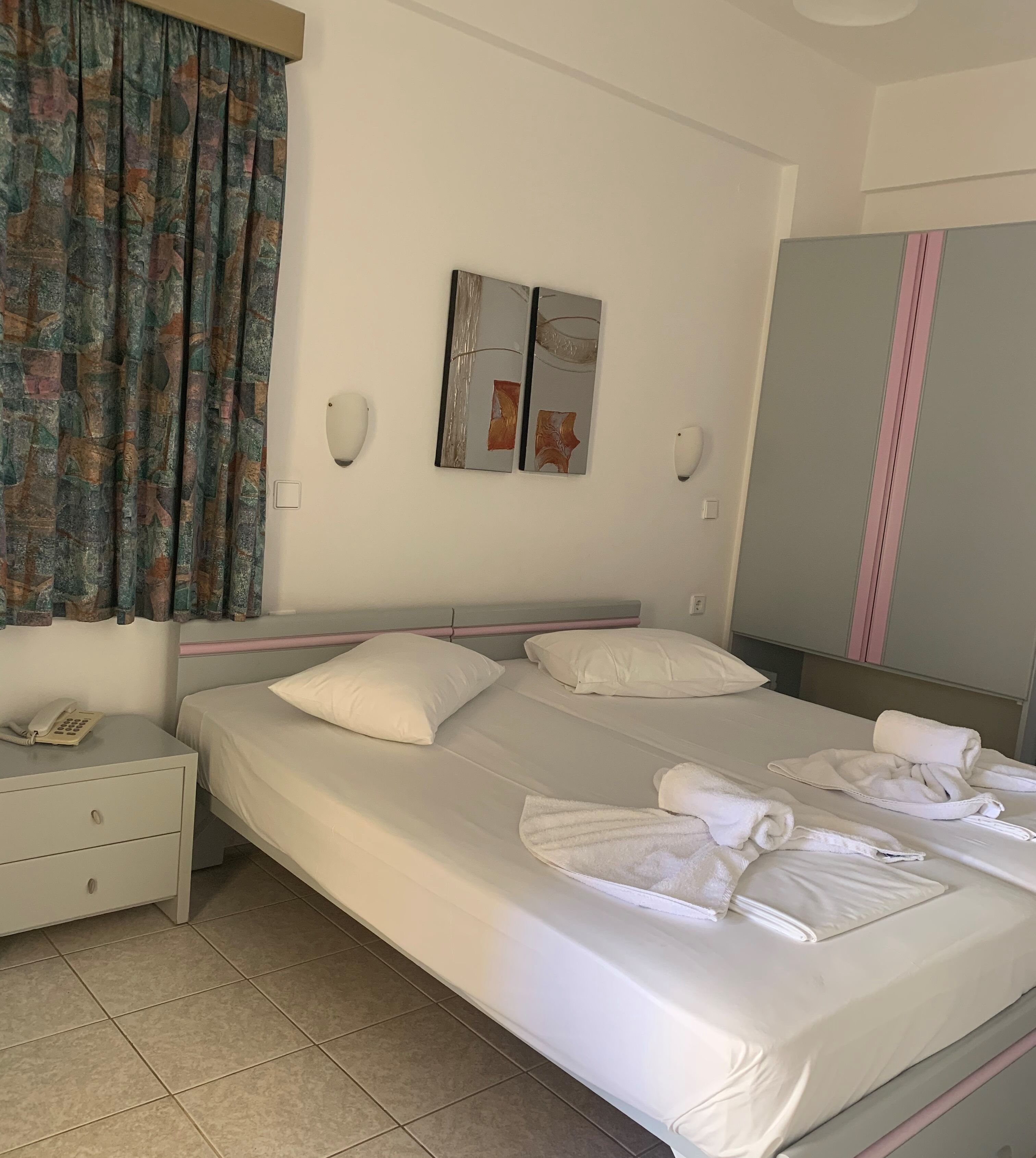 A hotel room with a bed, a nightstand, a telephone, and a mirror.