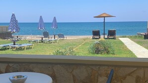 Un balcón con vista al mar, que incluye sillones de descanso, sombrillas y una mesa.