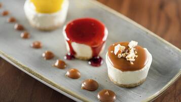Drei Desserts auf einem Teller mit Karamellsauce und roter Sauce.