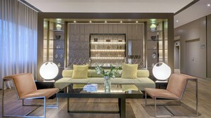 Una sala de estar moderna con un sofá, dos sillones, una mesa de centro y un jarrón decorativo.