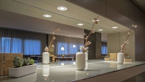 Una habitación de hotel moderna con un espejo grande, una mesa de vidrio y varias plantas en macetas.