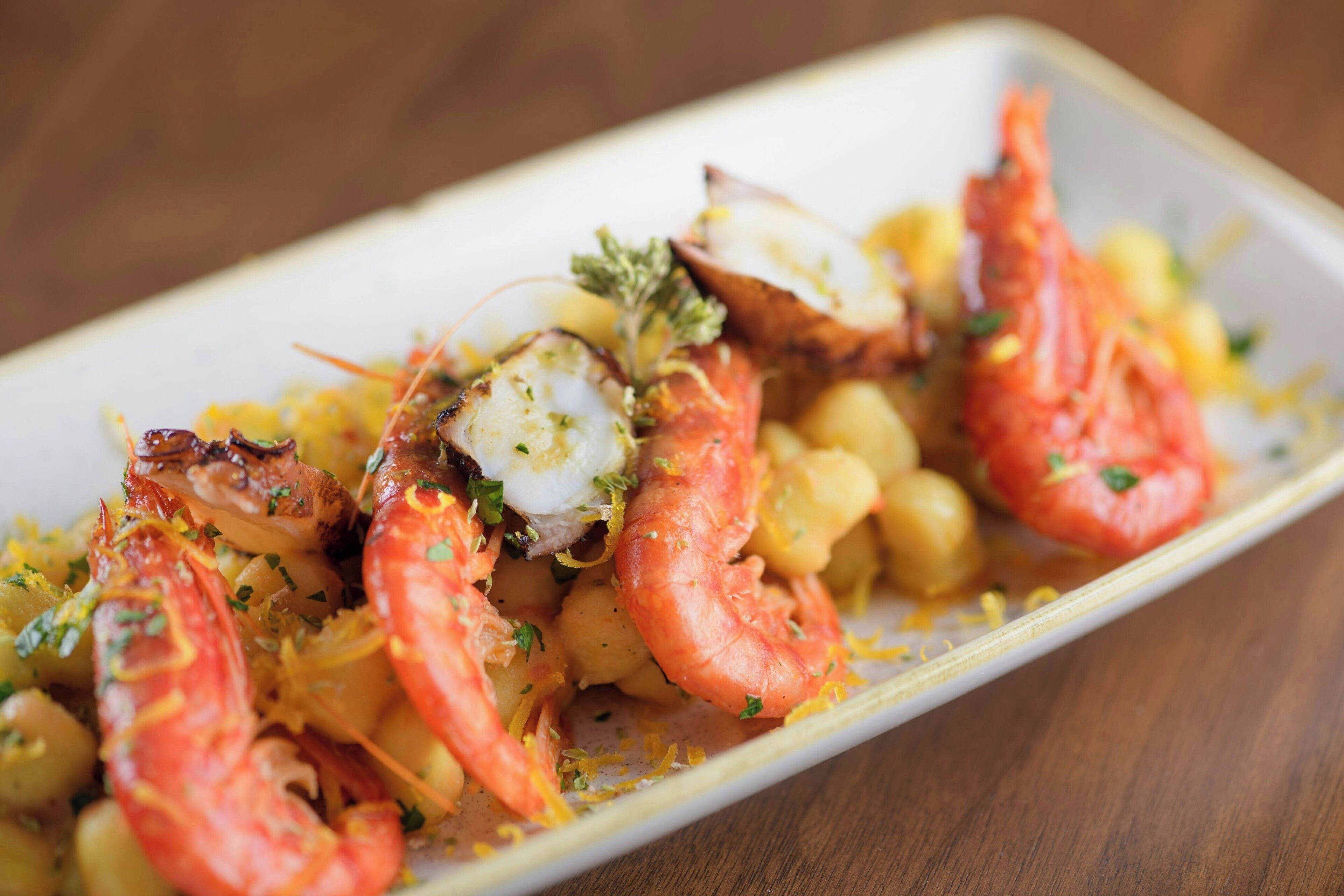 A dish with shrimp, scallops, and chickpeas on a plate.