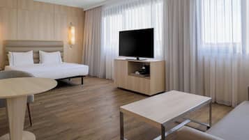 Et moderne hotelværelse med seng, fjernsyn, skrivebord og spisebord.
