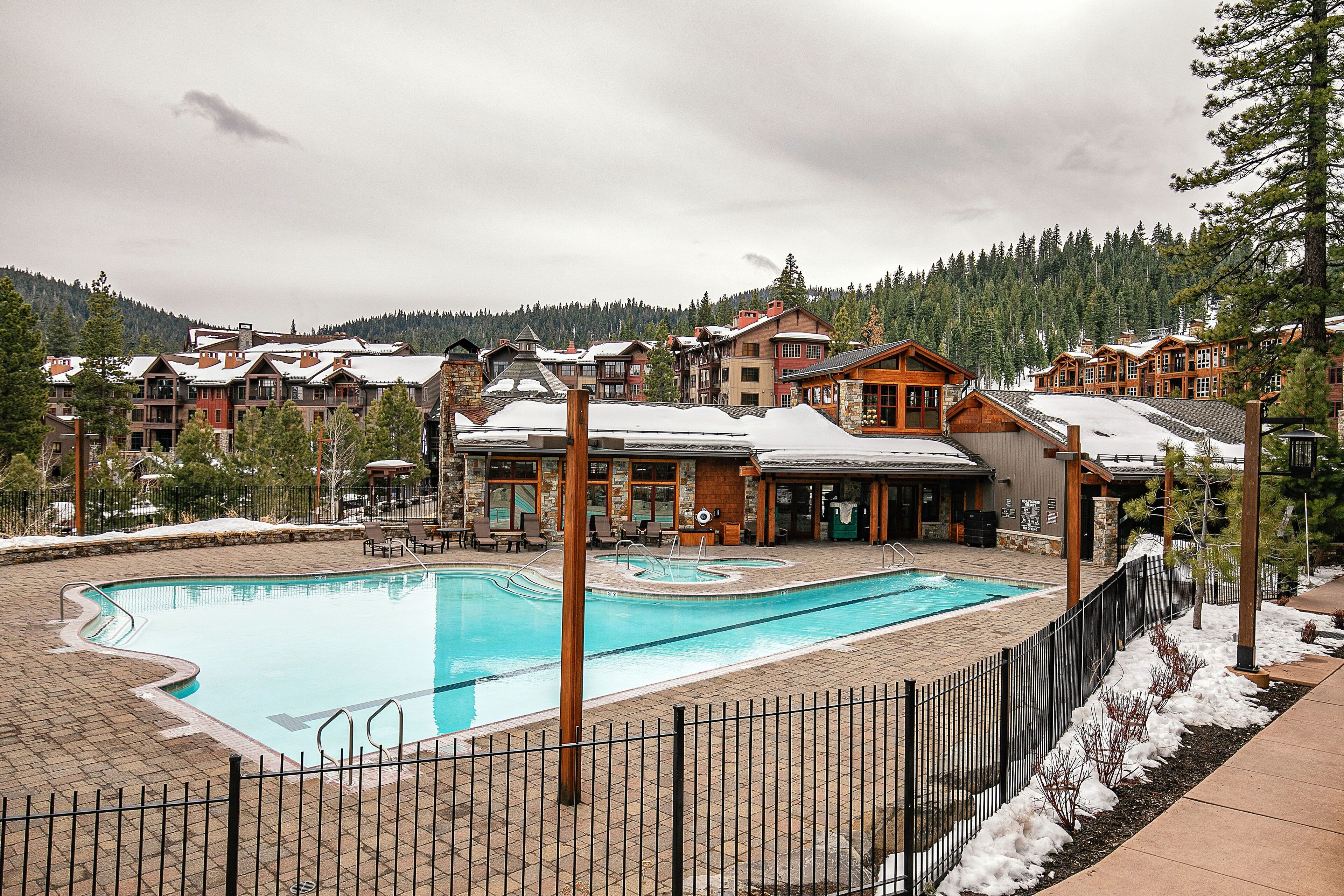 A resort with a swimming pool, multiple buildings, and a snowy landscape.