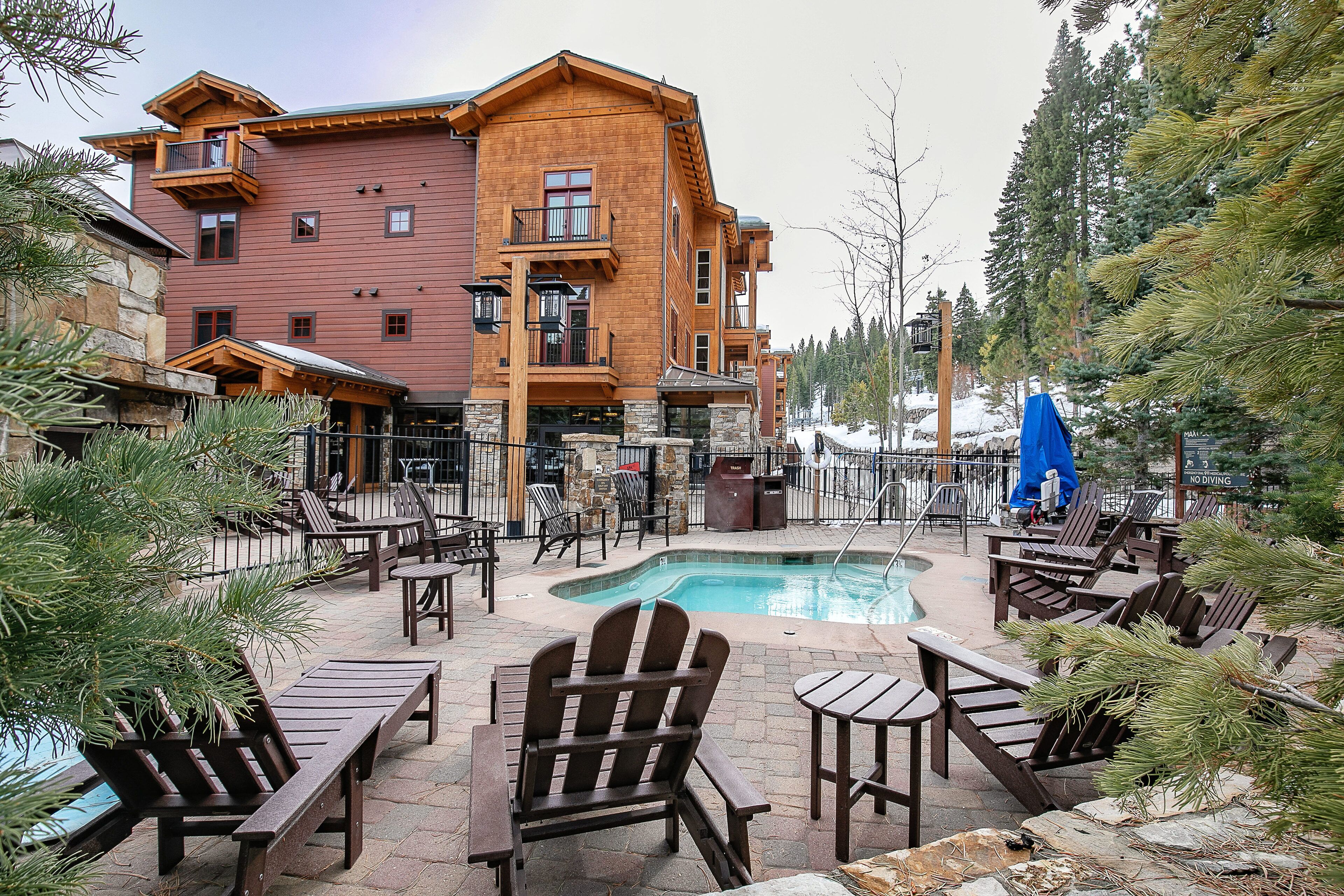 A lodge with a pool area, outdoor seating, and a large building with multiple balconies.