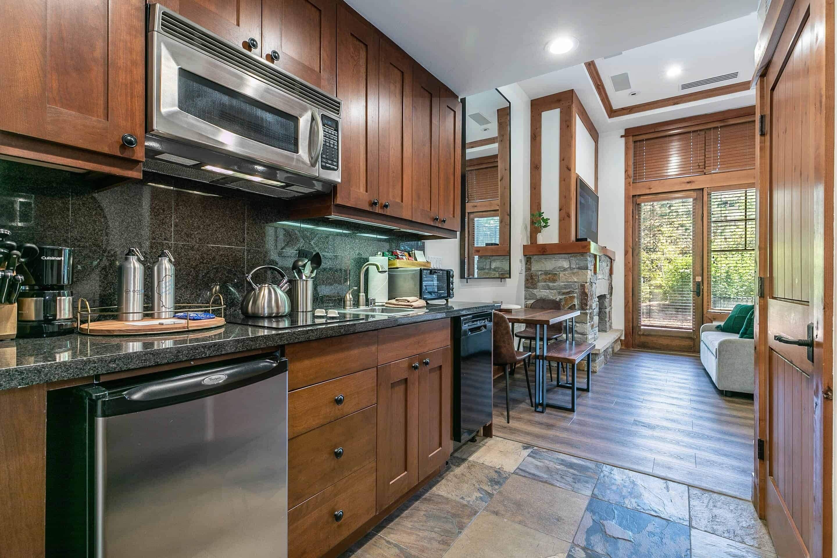 A modern kitchen with wooden cabinets, stainless steel appliances, and a stone backsplash.