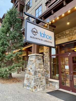 Segnale per Tahoe Mountain Lodging, con un pilastro in pietra e un grande albero sullo sfondo.