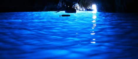 A pool with a blue hue, surrounded by a cave-like structure.