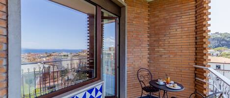A balcony with a view of the city, a table with chairs, and a tiled floor.