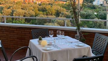 An outdoor dining area with a table set for four, overlooking a mountainous landscape.