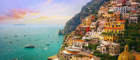 A coastal town with colorful buildings, a beach, and boats on the water.