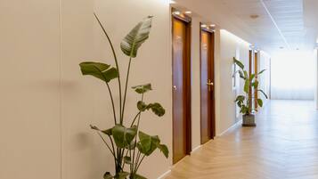 Un couloir avec un plancher en bois, des plantes en pot et des portes.