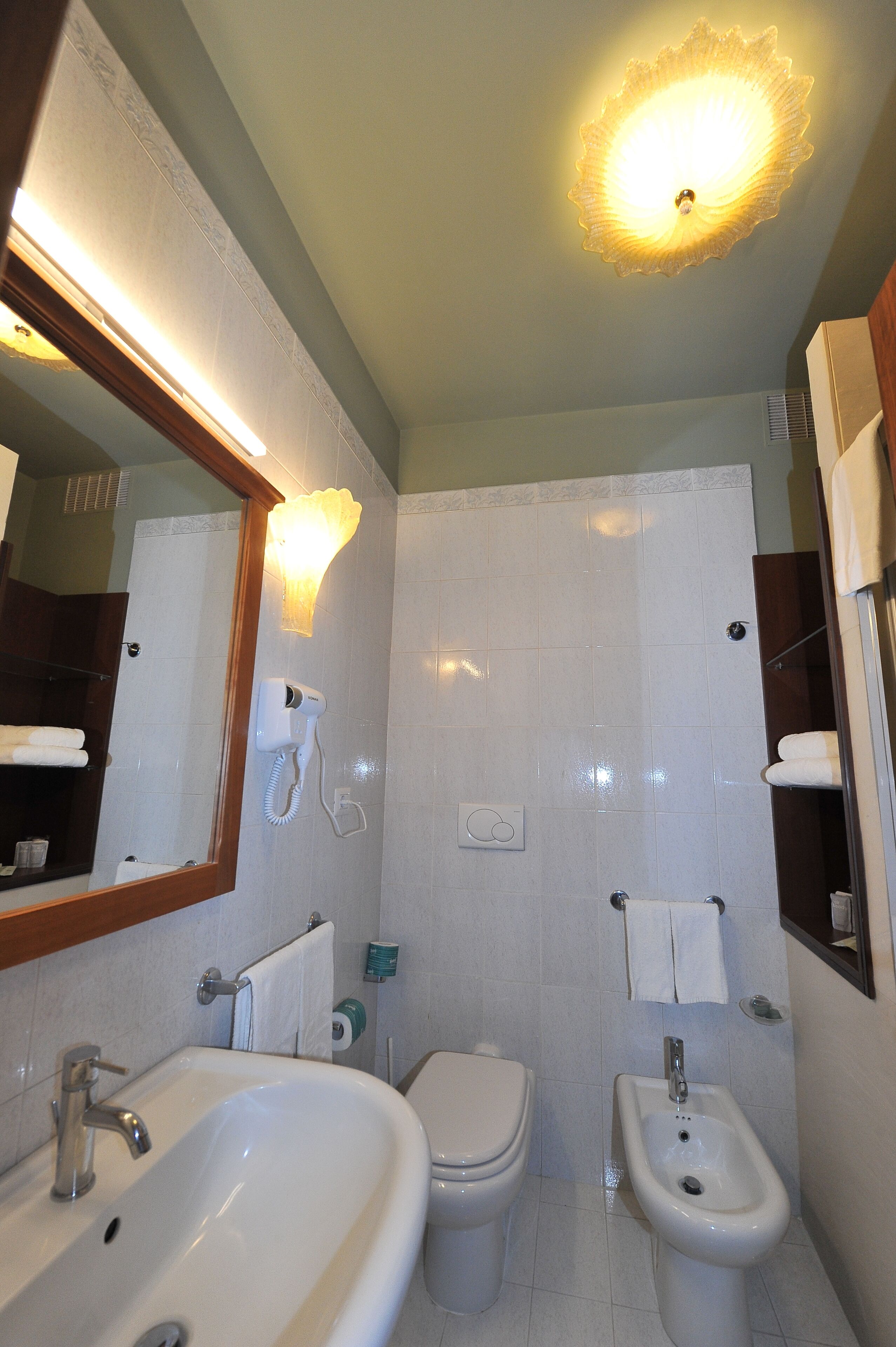 A bathroom with a sink, toilet, bidet, and a mirror.