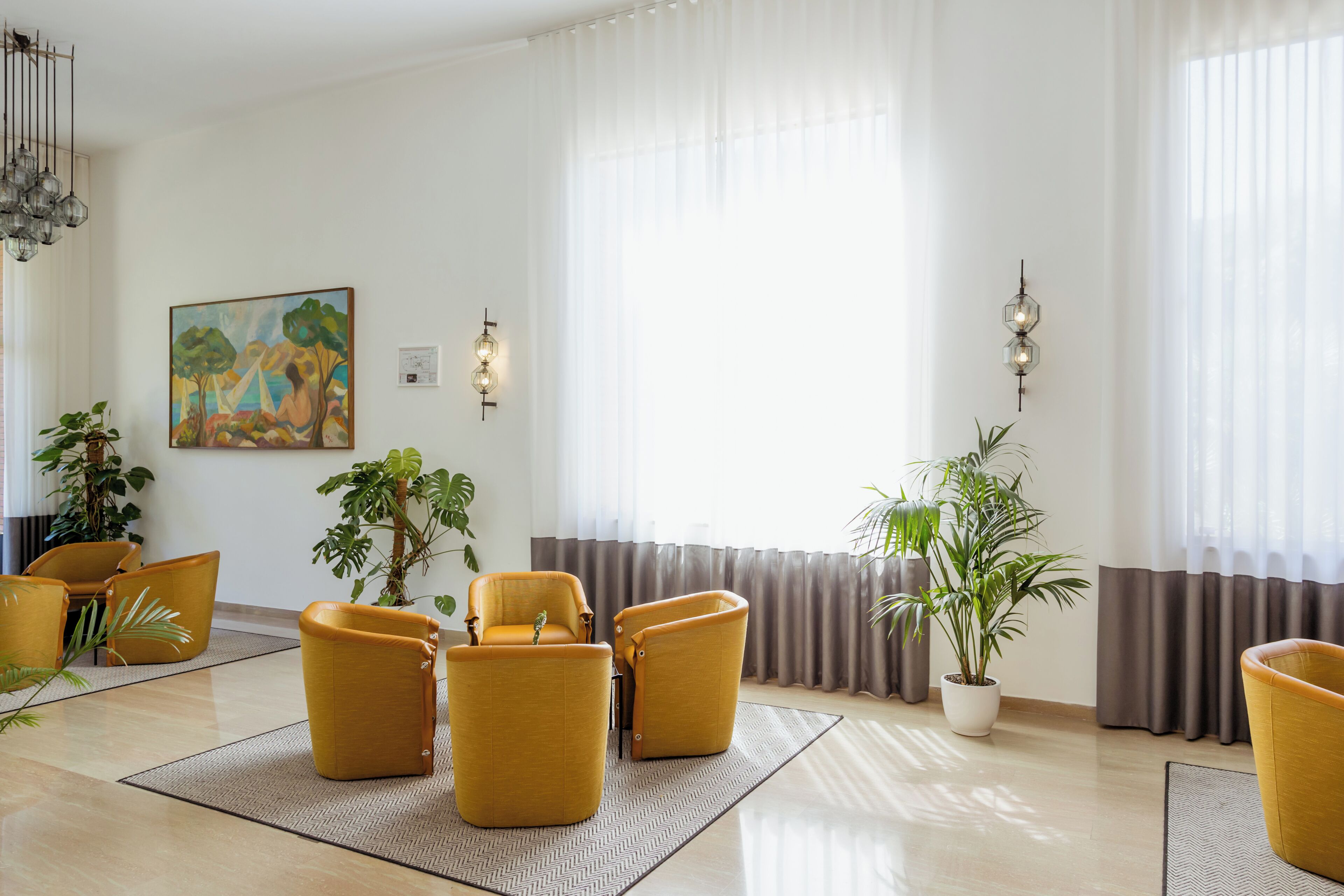 Een woonkamer met een groot raam, een schilderij en verschillende stoelen.