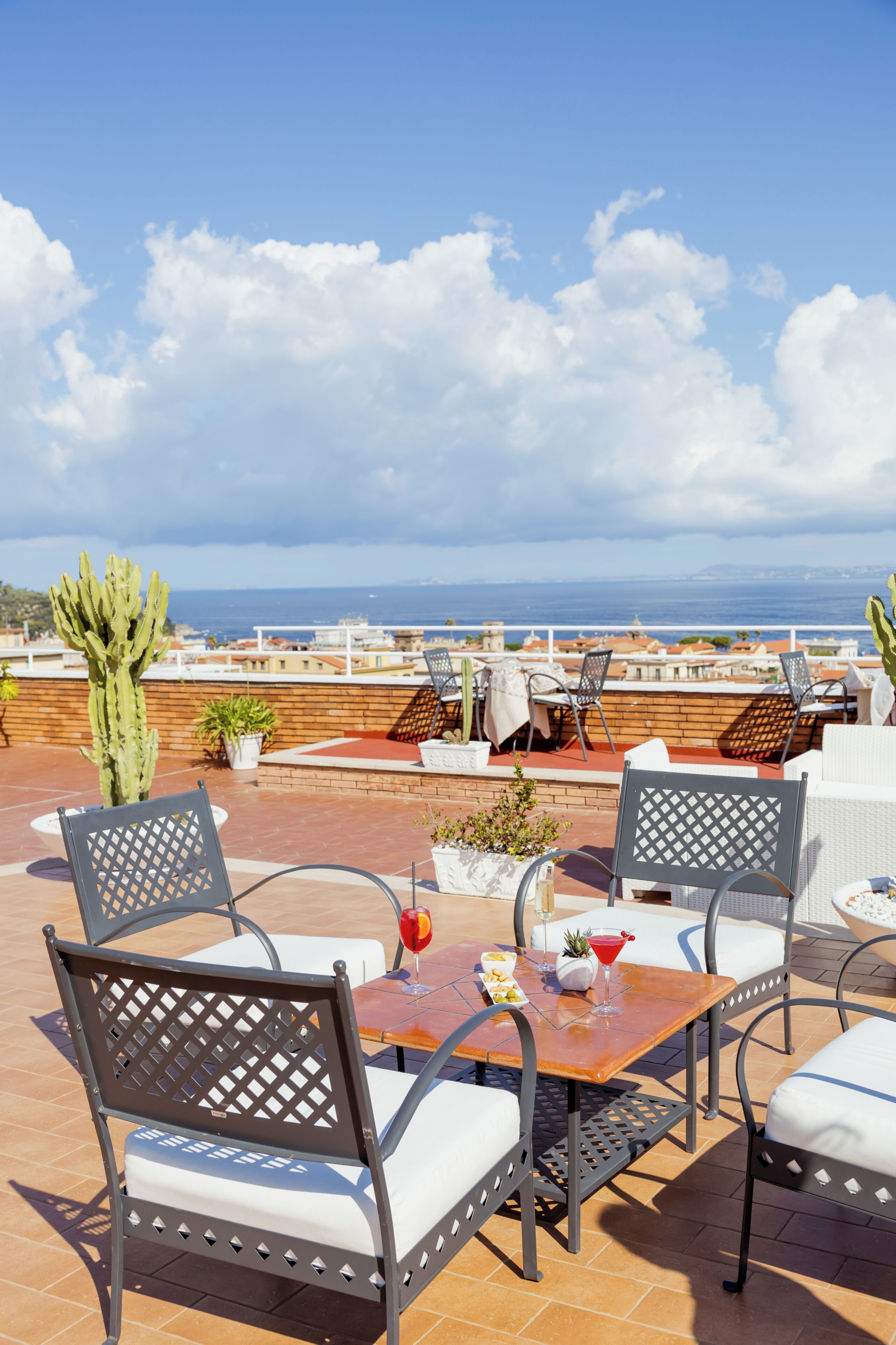 Una terraza con asientos exteriores, un cactus y vista al mar.