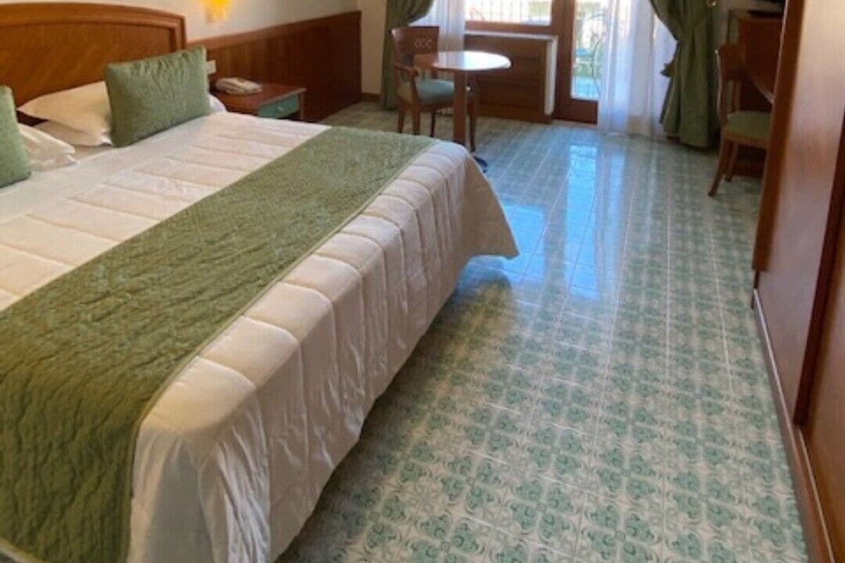 Une chambre d’hôtel avec un lit, un bureau, une chaise et une vue sur l’extérieur.