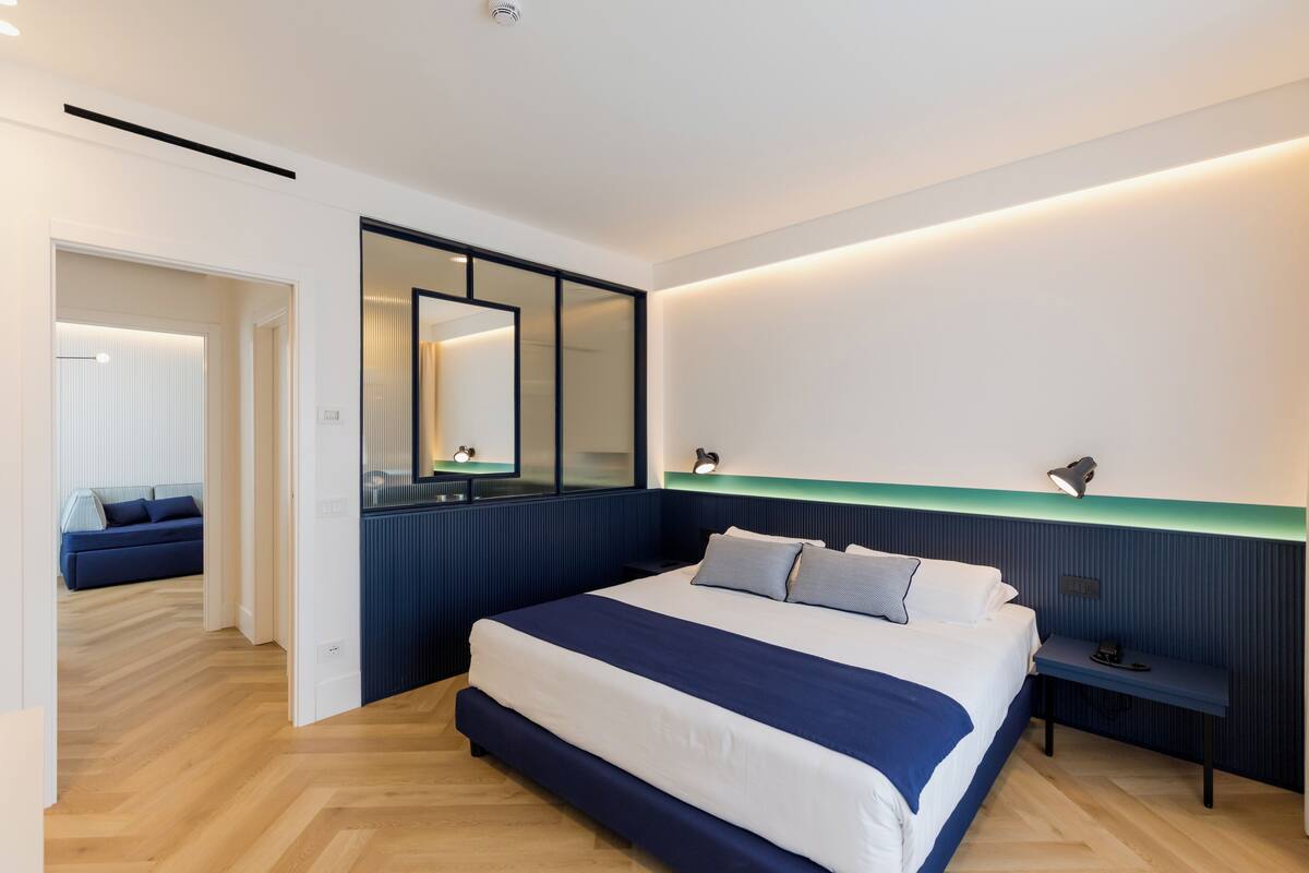 Une chambre à coucher moderne avec un grand lit, des tables de chevet et un miroir.