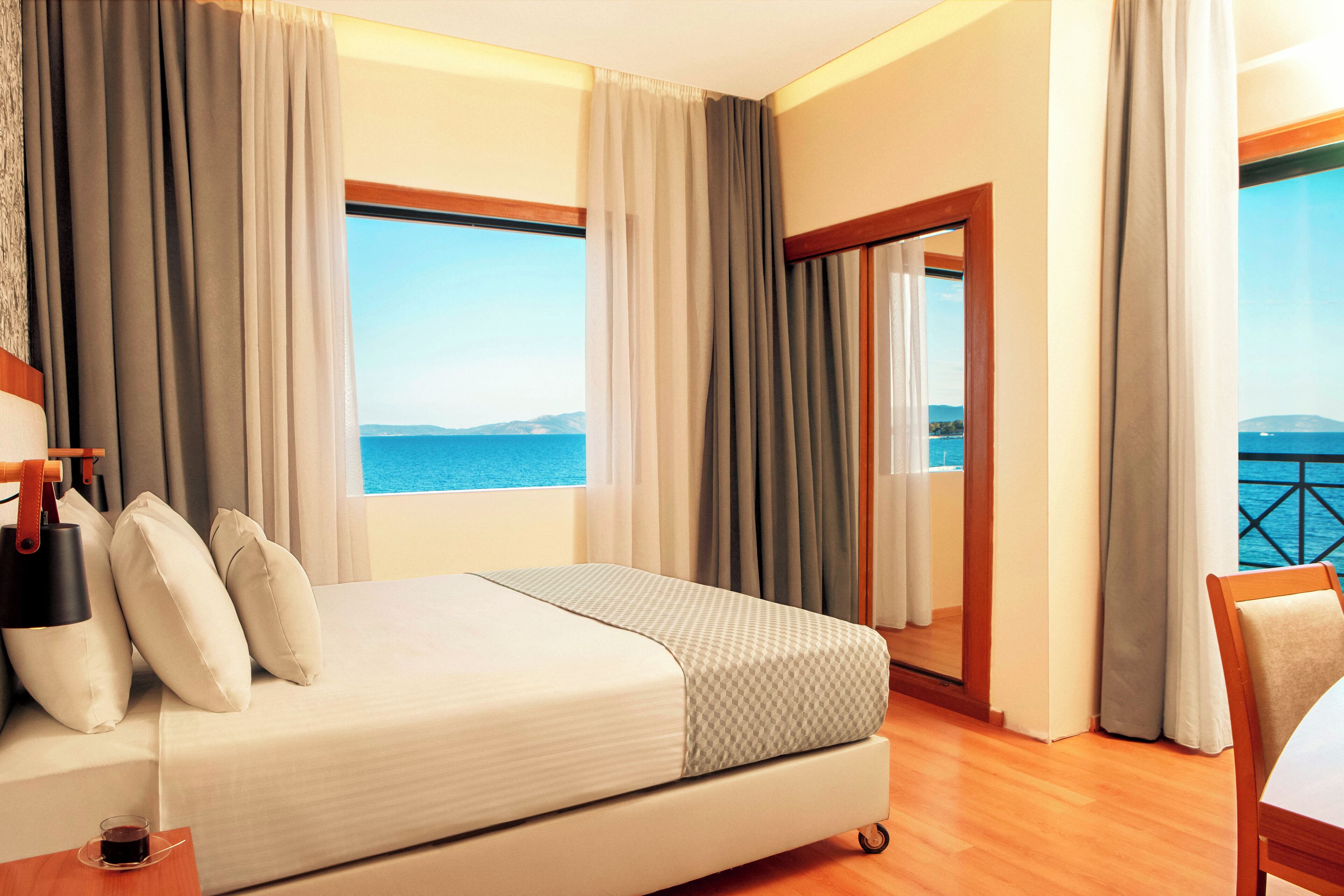 Habitación de hotel con cama, vistas al mar y balcón.