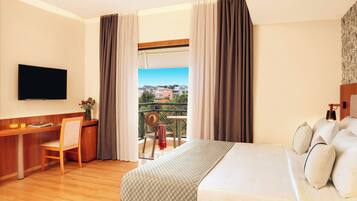 A hotel room with a bed, a desk, a chair, a TV, and a balcony with a view.