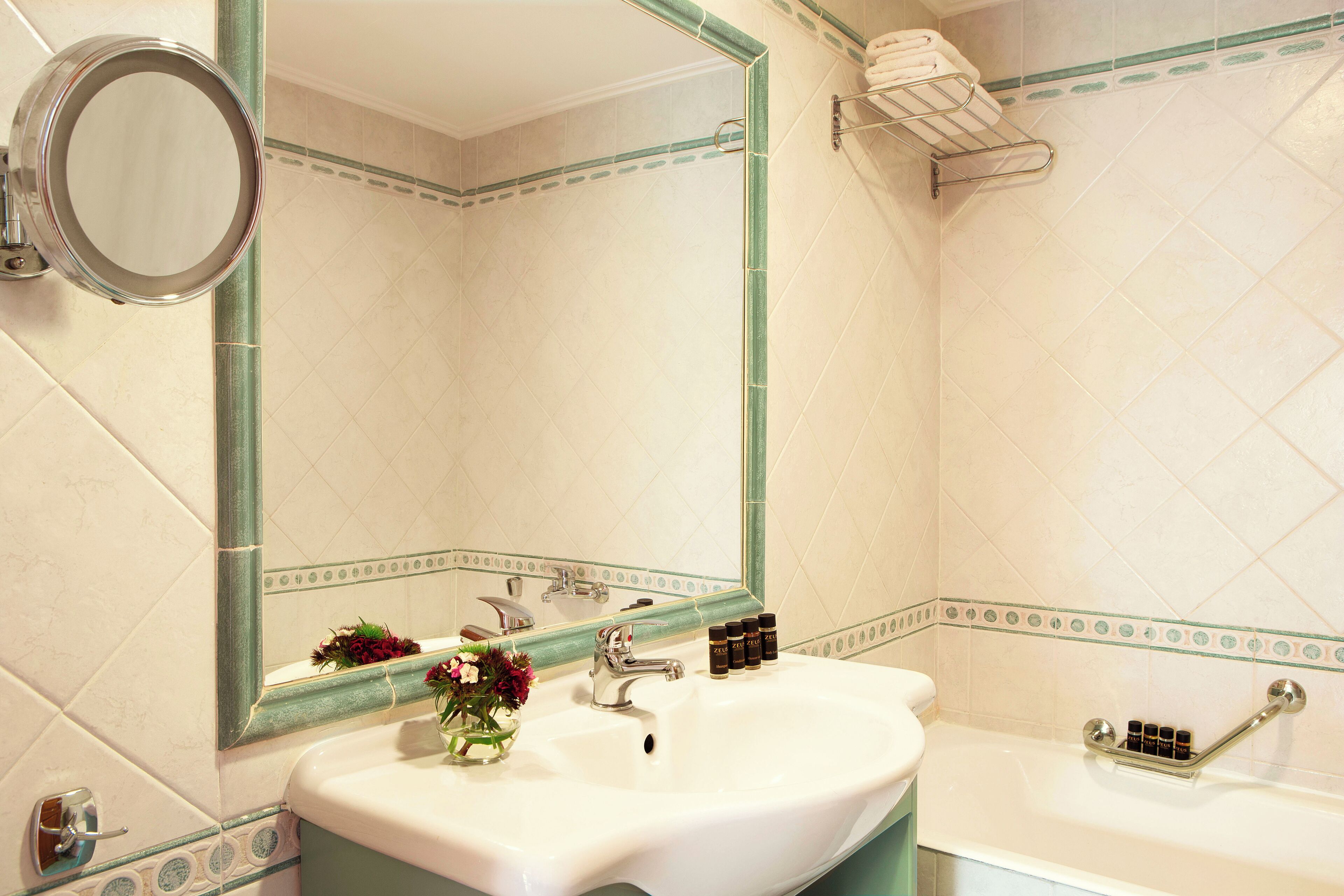 Un baño con lavamanos blanco, un espejo y una bañera.