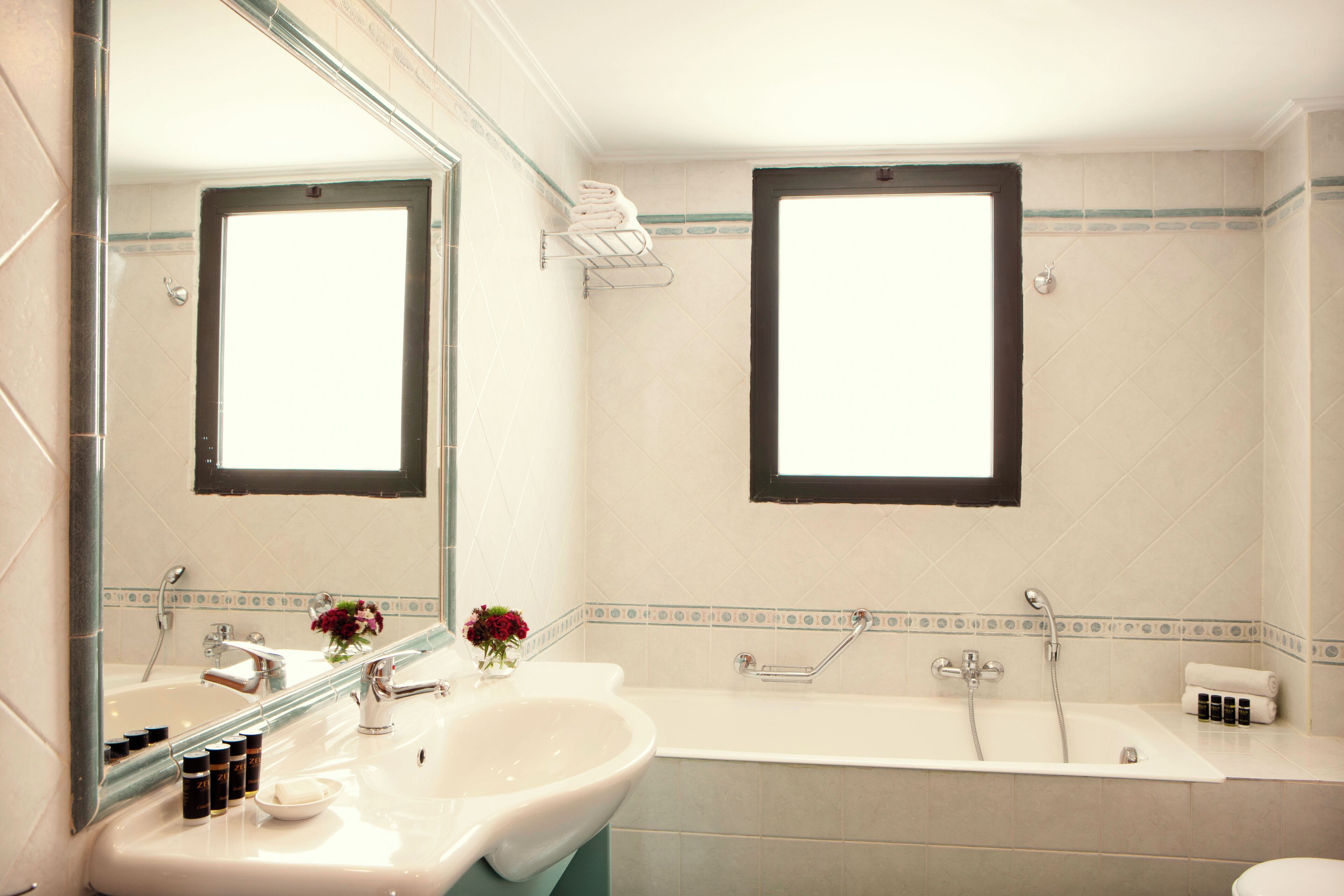 A bathroom with a sink, mirror, and bathtub.