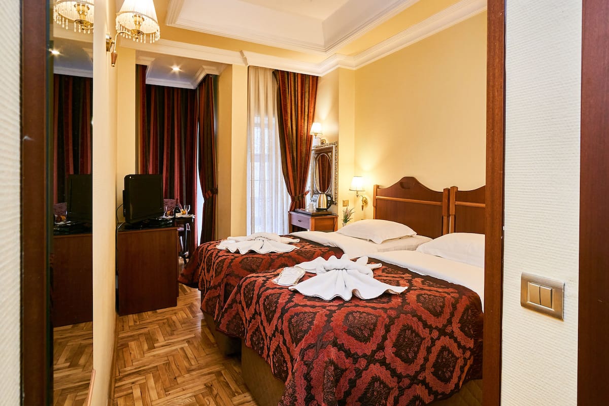 A hotel room with two beds, a desk, a television, and a mirror.