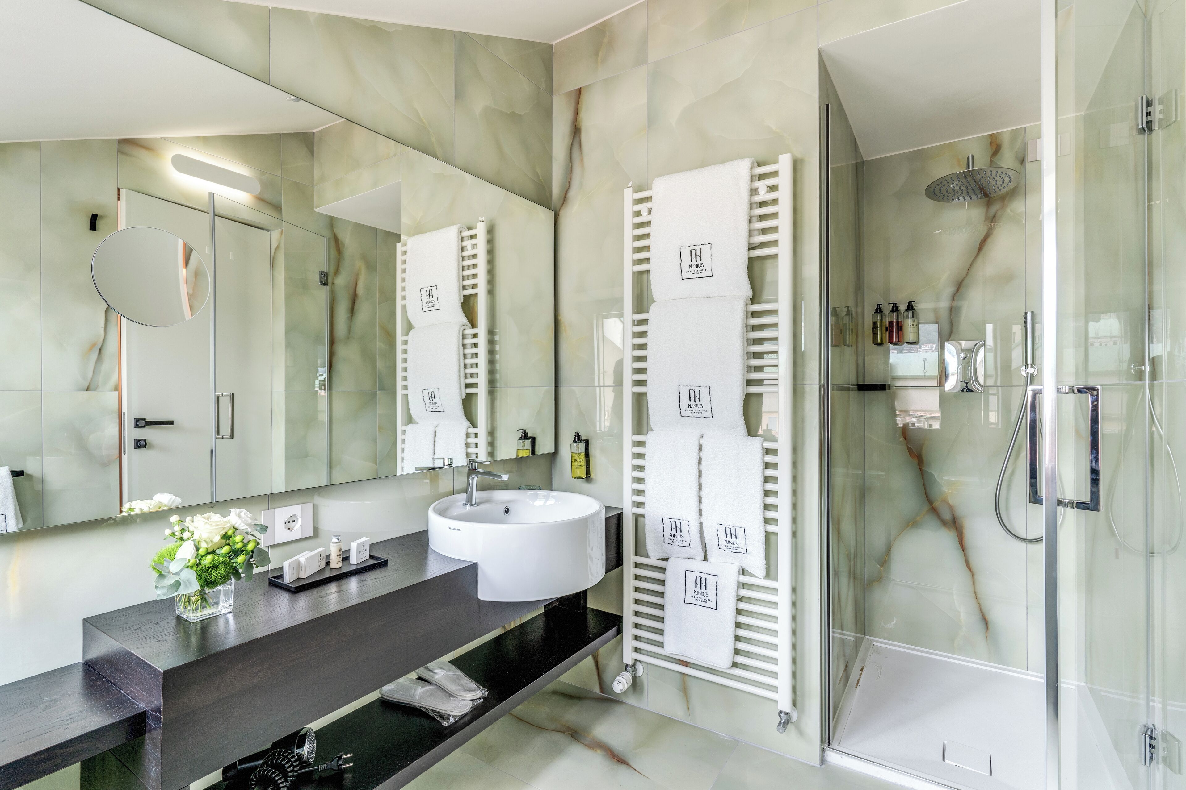 A modern bathroom with a large mirror, white sink, and glass shower enclosure.
