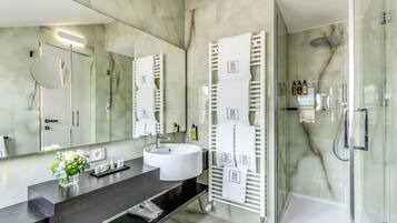 A modern bathroom with a large mirror, white sink, and glass shower enclosure.