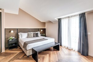 Ein modernes Hotelzimmer mit einem großen Bett, Holzboden, einem Nachttisch mit Lampe und einem Fenster mit Vorhängen.