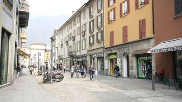A street with buildings, a café, and people walking.