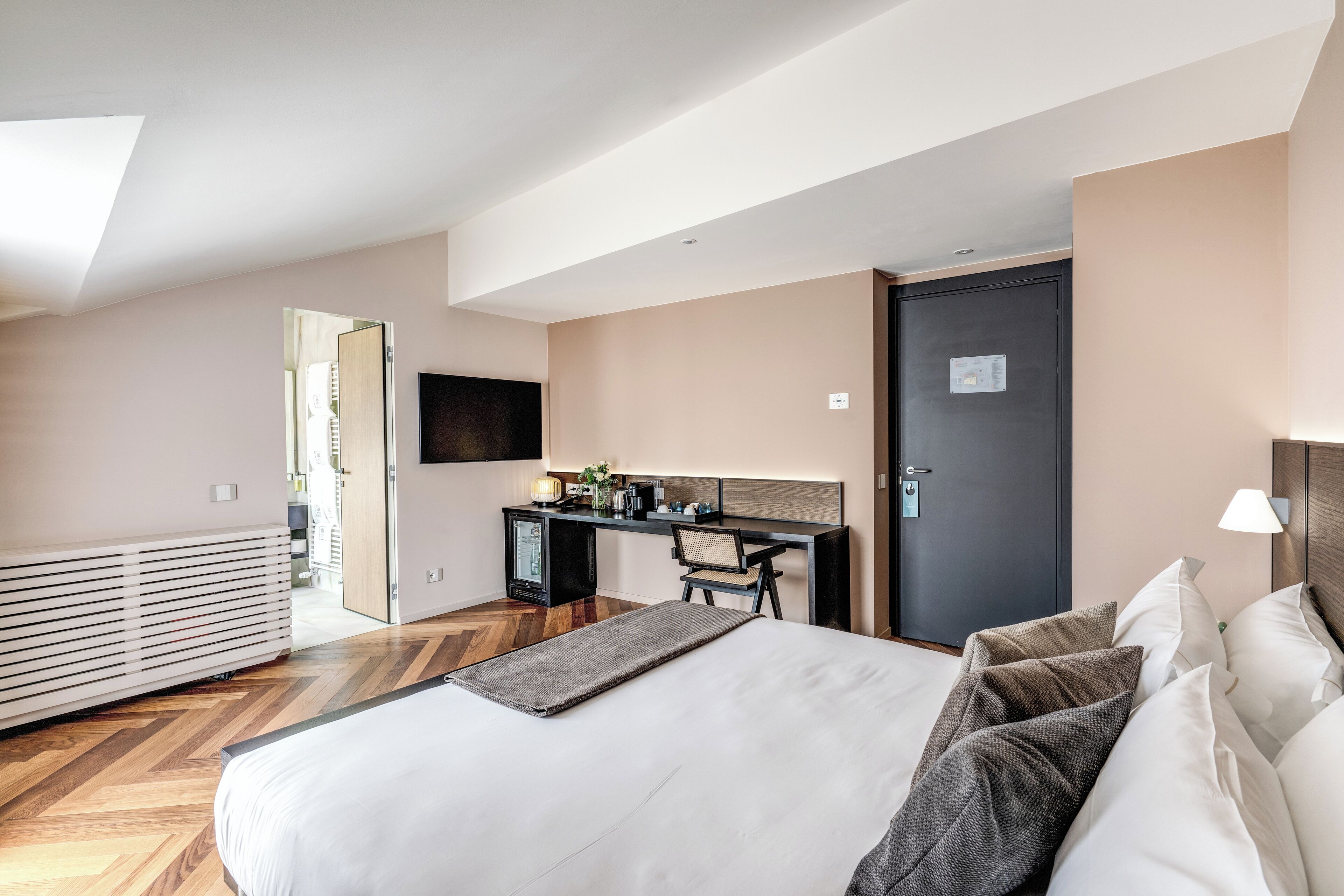Moderni hotellihuone, jossa on suuri sänky, työpöytä ja televisio.
