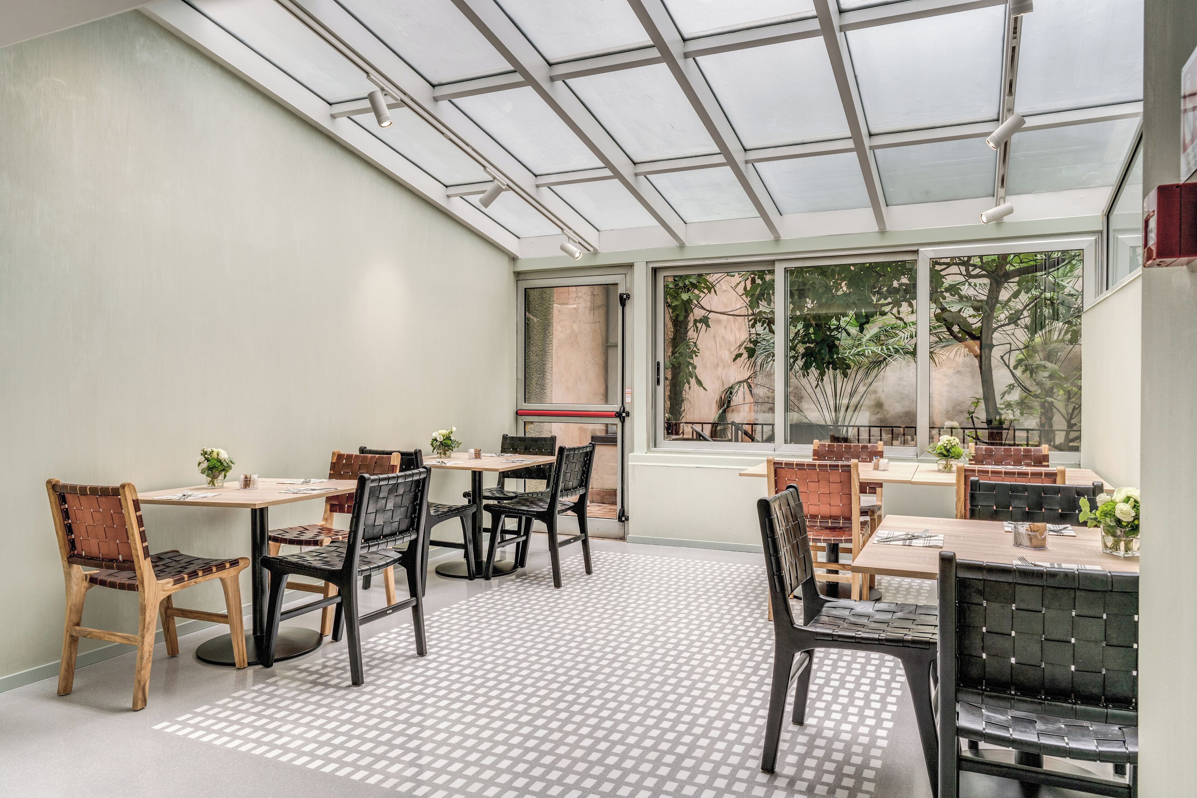 A dining area with tables and chairs, a glass ceiling, and large windows.
