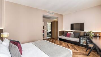 Una habitación de hotel moderna con una cama grande, un sofá, una mesa de comedor y un televisor montado en la pared.