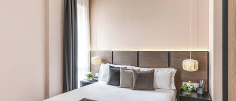 Habitación de hotel moderna con una cama grande, una mesita de noche con lámpara y un mueble auxiliar con control remoto.