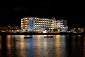 A multi-story hotel with balconies, a waterfront view, and a sign reading 'Allia Soll.'