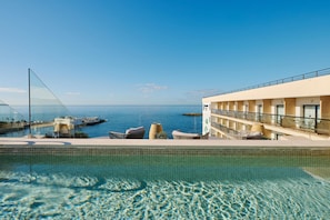 A pool with clear water, a balcony with seating, and a view of the sea. - AluaSoul Palma - Adults Only (Palma de Mallorca)
