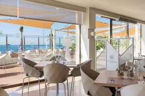 A restaurant with a view of the sea, tables with chairs, and umbrellas. - AluaSoul Palma - Adults Only (Palma de Mallorca)