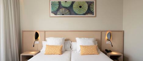 Una cama doble con dos almohadas, una mesita de noche con un teléfono y una obra de arte colgada en la pared.